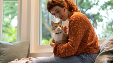 Femme portant un chandail orange et tenant un chat