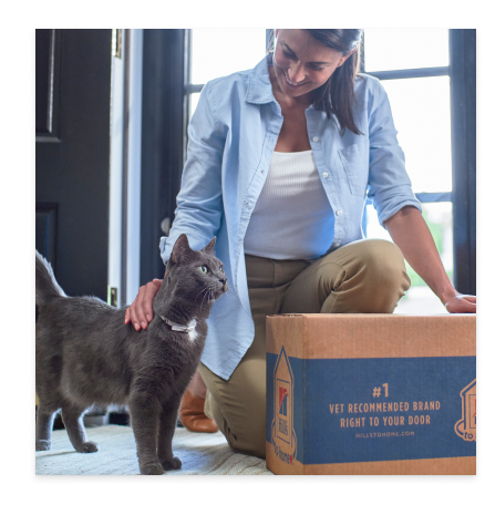 Une femme avec son chat noir et un emballage de nourriture pour chats Hill’s Pet